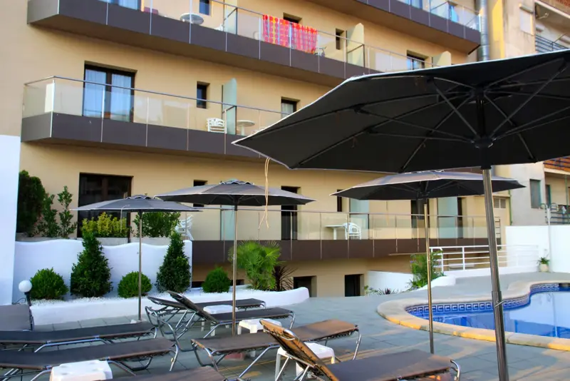 Transats et parasols ombragent une terrasse près d'une piscine.
