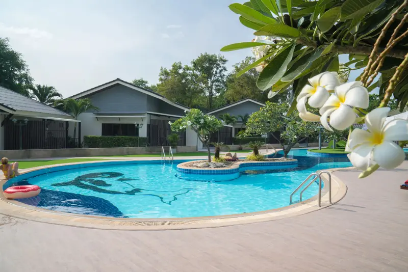 Une piscine rectangulaire avec un îlot central et des transats sur une terrasse.