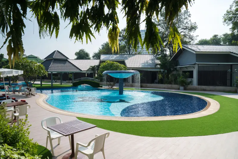 Piscine circulaire avec cascade et mobilier de jardin.