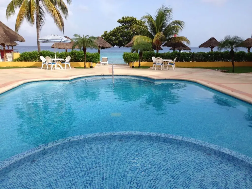 Piscine bleue bordée d'une terrasse ensoleillée avec vue sur la mer.