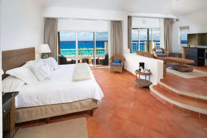 Une chambre lumineuse avec un grand lit donnant sur une vue mer.