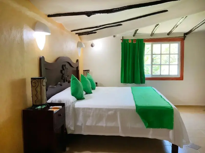 Une chambre lumineuse avec un grand lit recouvert de linge blanc et vert.