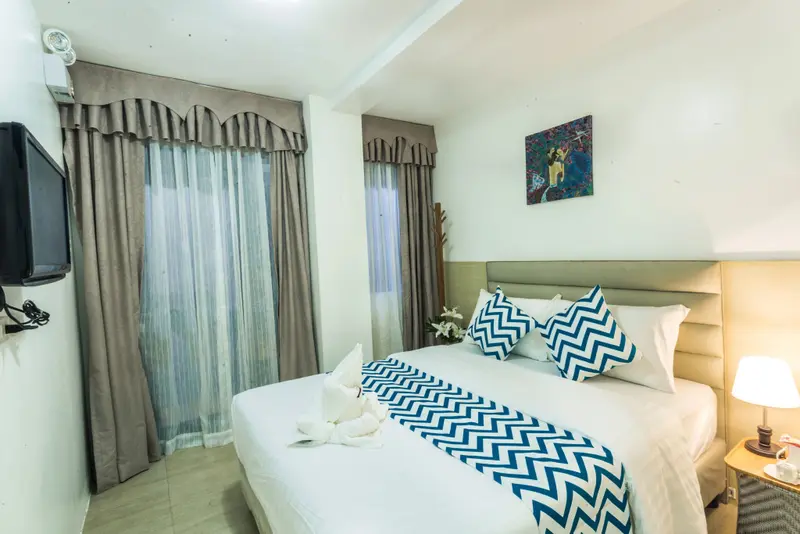 Une chambre lumineuse avec un grand lit recouvert d'une courtepointe à motifs.
