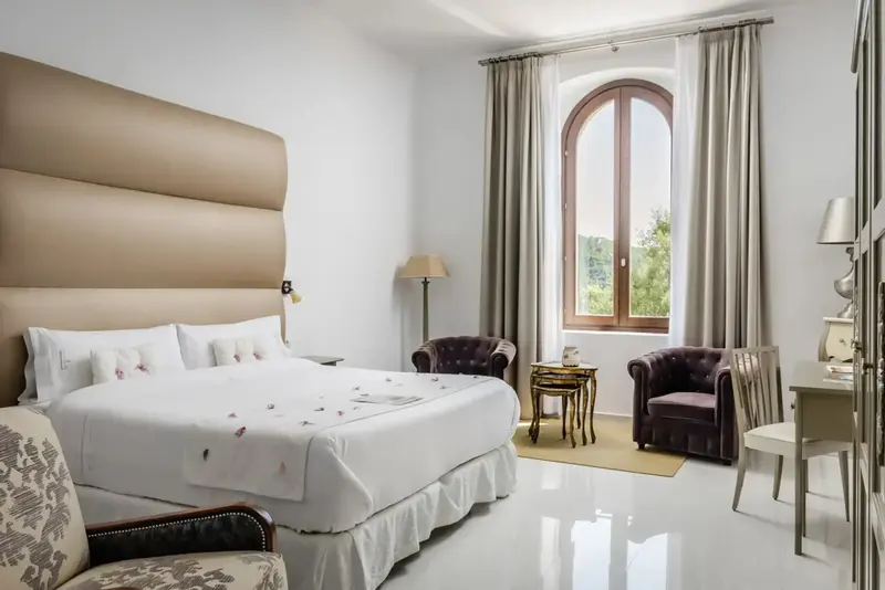 Une chambre lumineuse avec un grand lit et deux fauteuils.
