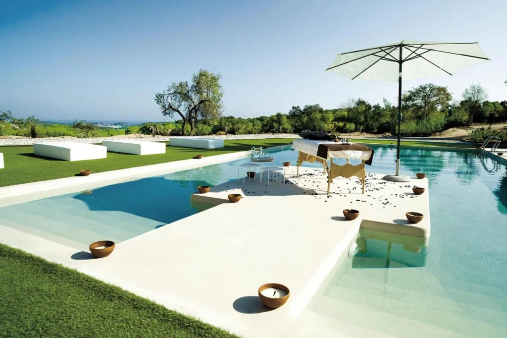 Une piscine rectangulaire avec un espace de repos aménagé au centre.
