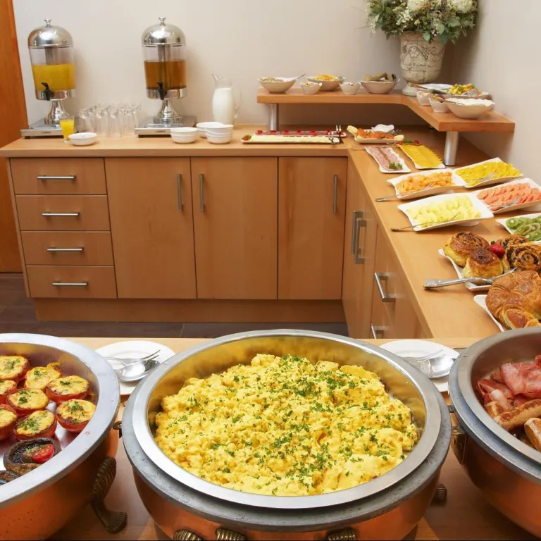 Un buffet propose des œufs brouillés, des viennoiseries et des fruits frais.
