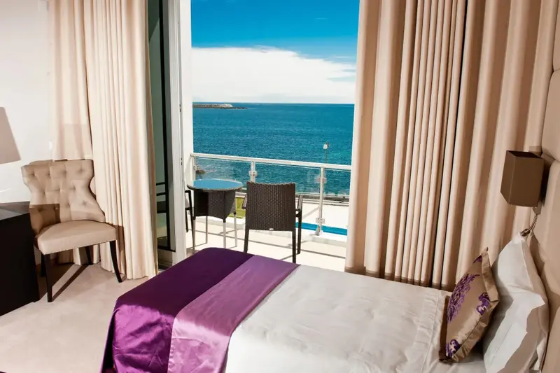 Une chambre lumineuse s'ouvre sur une terrasse avec vue sur la mer.