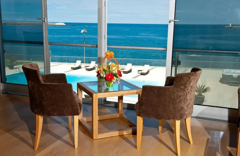 Deux fauteuils face à une large baie vitrée donnant sur la mer et une piscine.