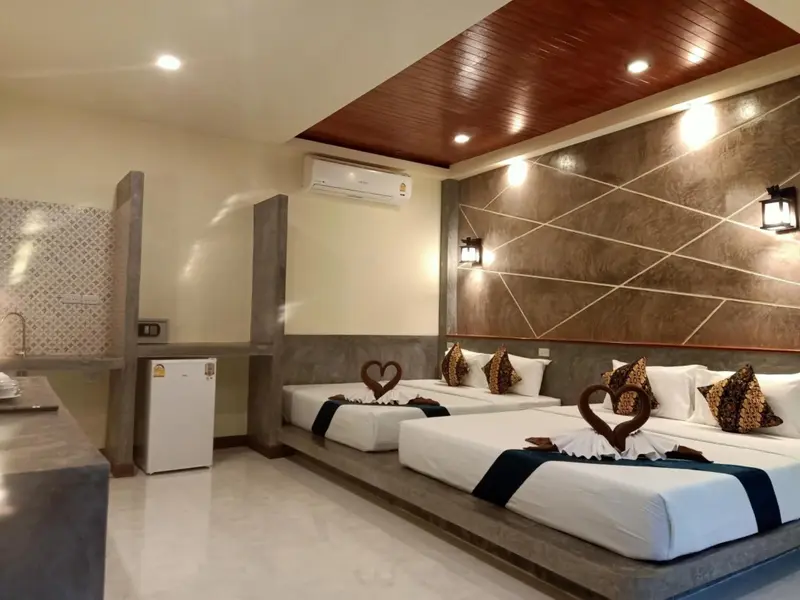 Une chambre lumineuse avec deux lits décorés de cœurs et un coin cuisine.