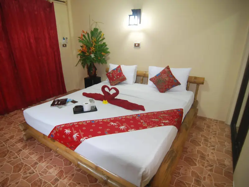 Une chambre lumineuse avec un grand lit recouvert de draps blancs et de décorations florales.