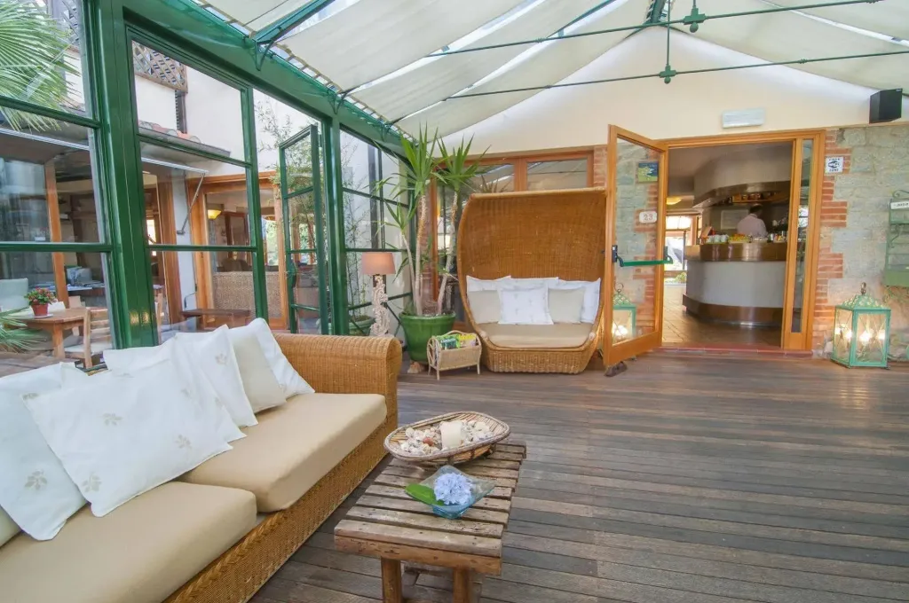 Espace de détente lumineux avec canapés et mobilier en rotin.