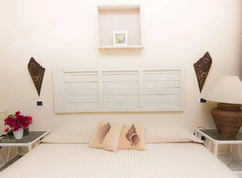Une chambre lumineuse avec un lit recouvert de coussins rayés et décorée de motifs floraux.