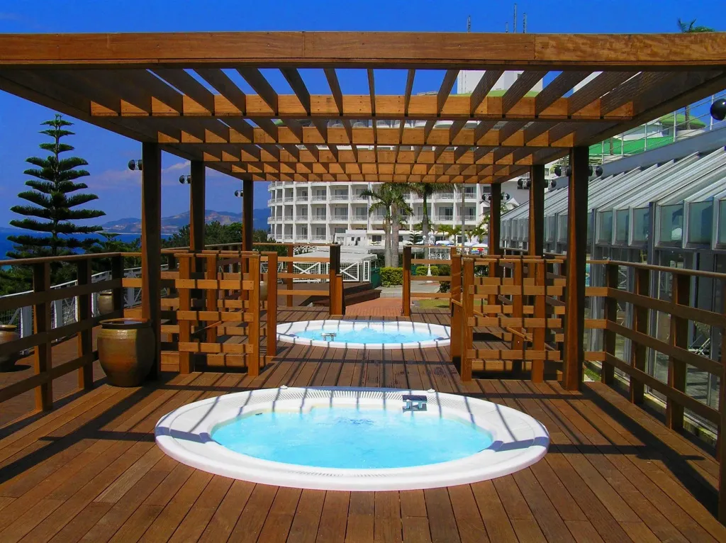 Terrasse en bois avec plusieurs jacuzzis et vue sur la mer.