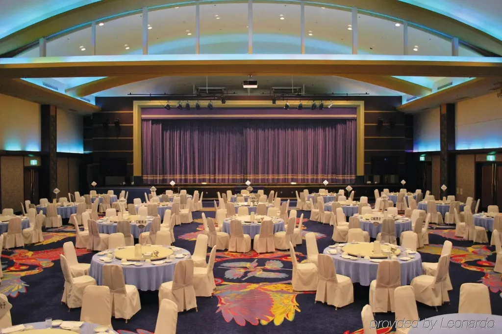 Grande salle de réception avec tables rondes nappées et rideau violet.