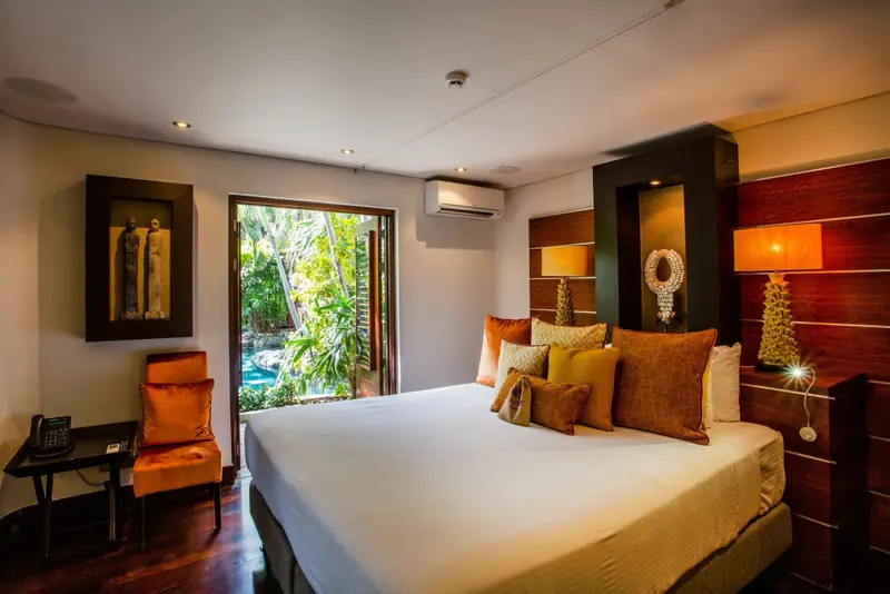 Une chambre lumineuse avec un grand lit et un accès à une végétation luxuriante.