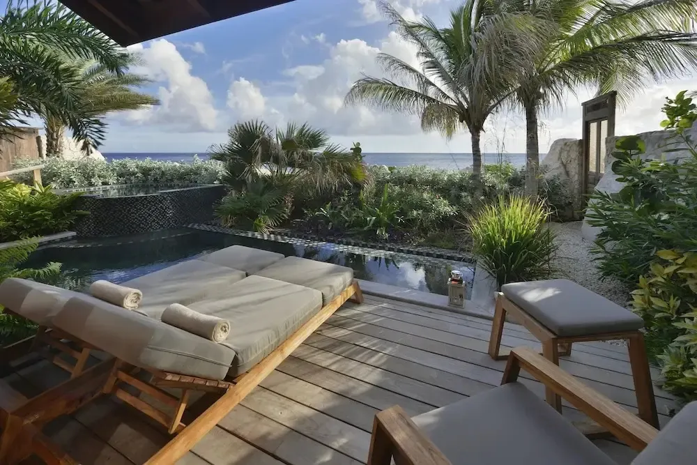 Transats confortables sur une terrasse en bois avec piscine et vue sur la mer.