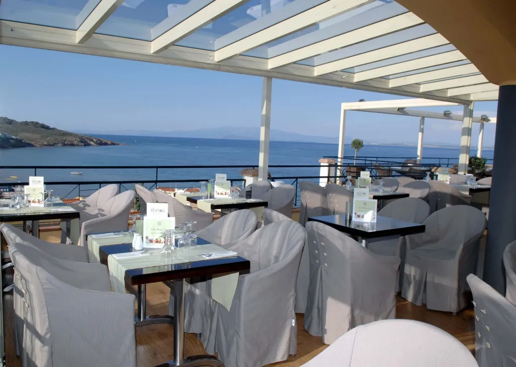 Une terrasse ombragée avec des tables et des chaises face à la mer.