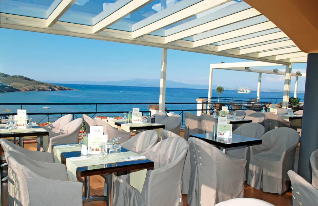 Une salle à manger extérieure avec des tables dressées face à la mer.