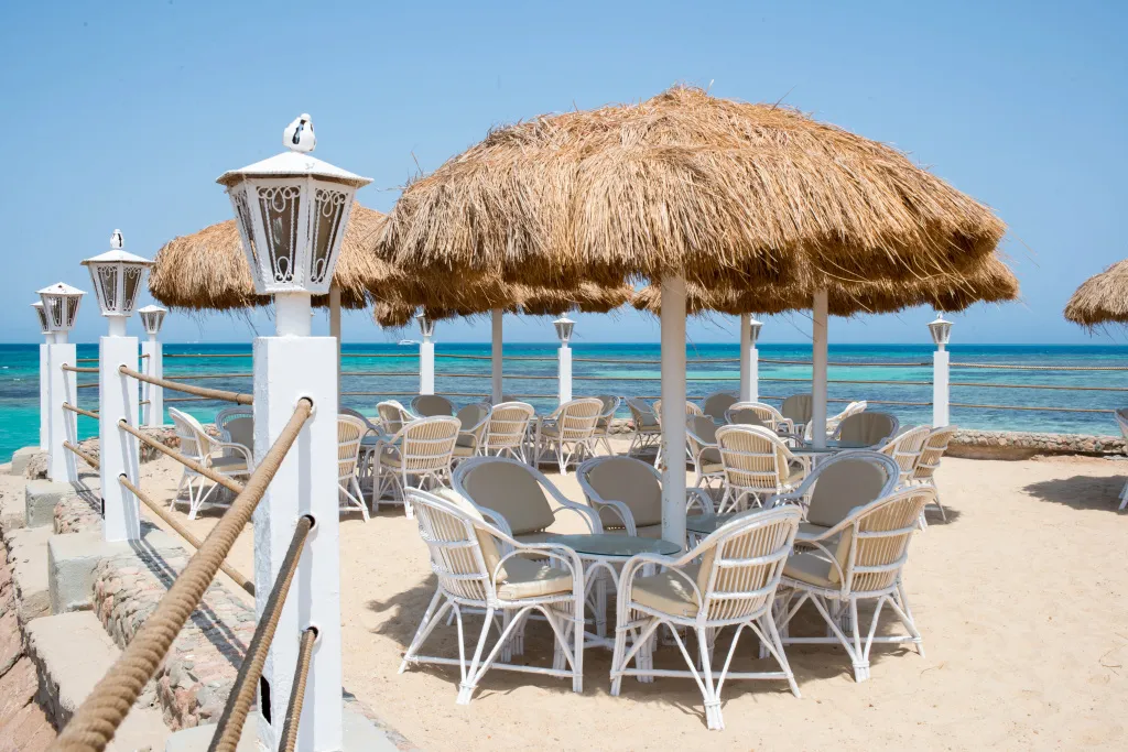 Terrasse ombragée avec tables et chaises en bord de mer.