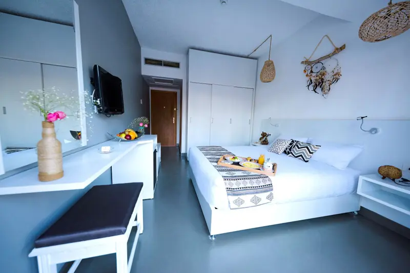 Une chambre lumineuse avec un lit décoré et un coin repas.