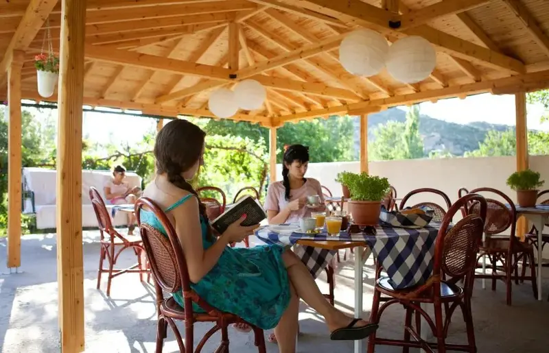 Des personnes sont assises à une table sous une pergola en bois.