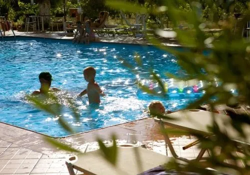 Une piscine ensoleillée avec des personnes se baignant et des transats à proximité.