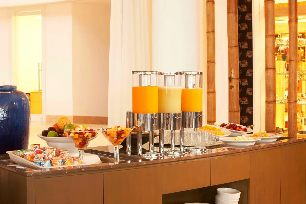 Un buffet propose des fruits frais et des jus de fruits.