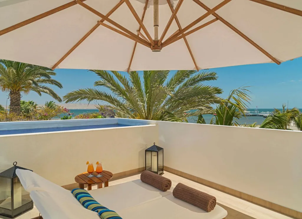Terrasse ombragée avec transats et vue sur la mer.