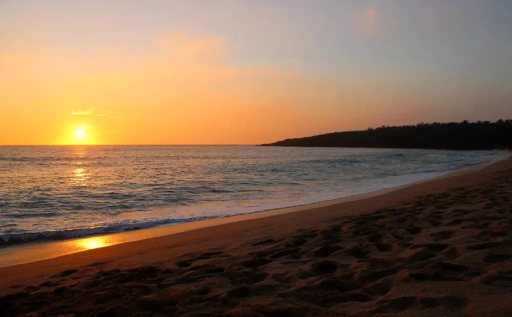 Le soleil se couche sur une plage de sable fin.