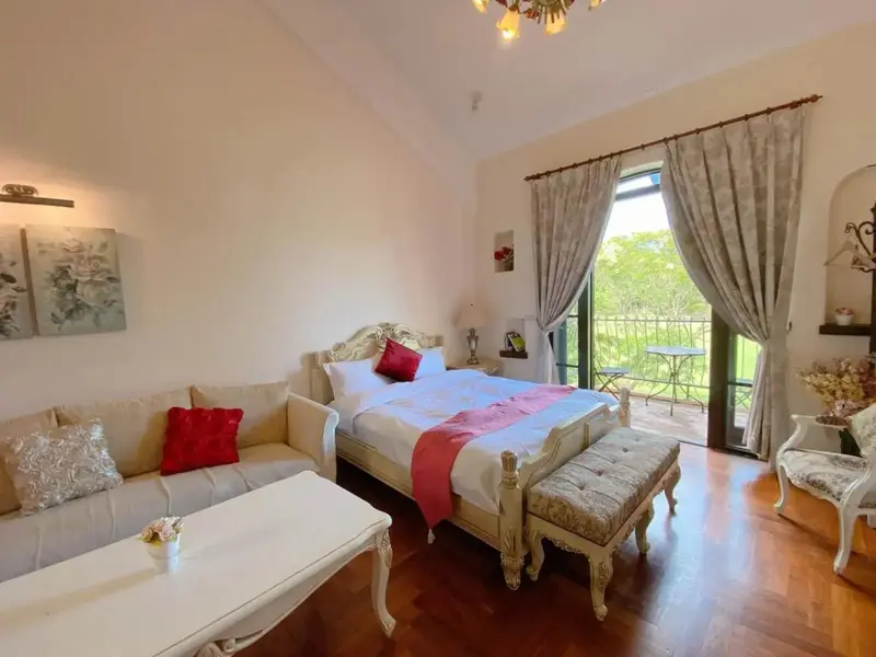 Une chambre lumineuse avec un lit à baldaquin et un coin salon.