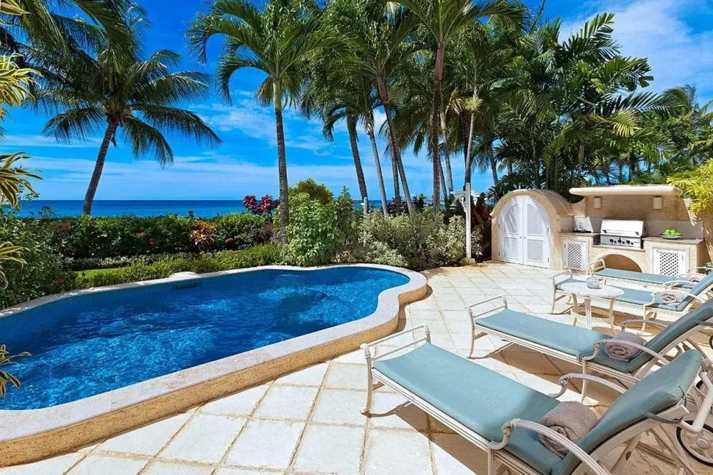 Une piscine turquoise bordée d'une terrasse ensoleillée avec des transats.