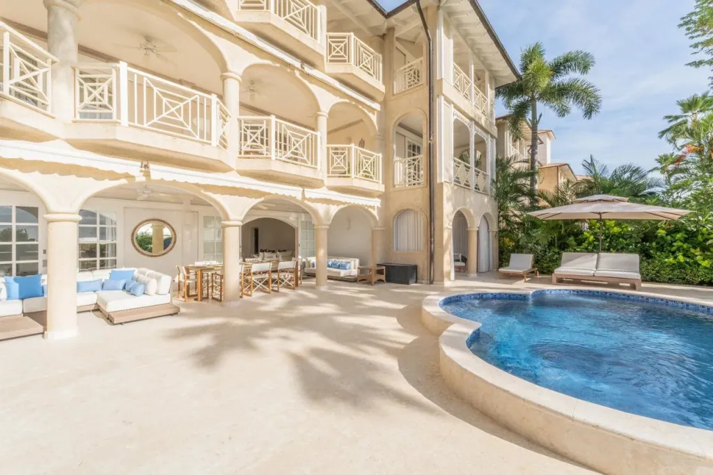 Terrasse ombragée avec salon et piscine.
