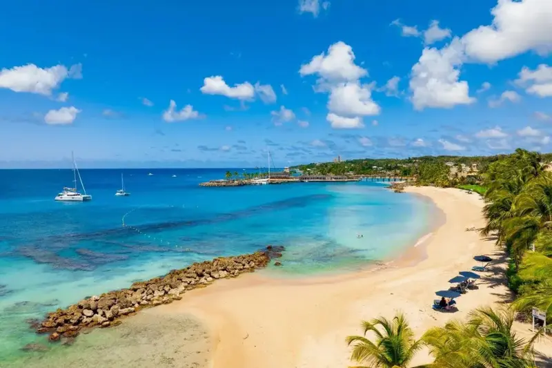 Une plage de sable fin bordée d'une eau turquoise et de végétation luxuriante.