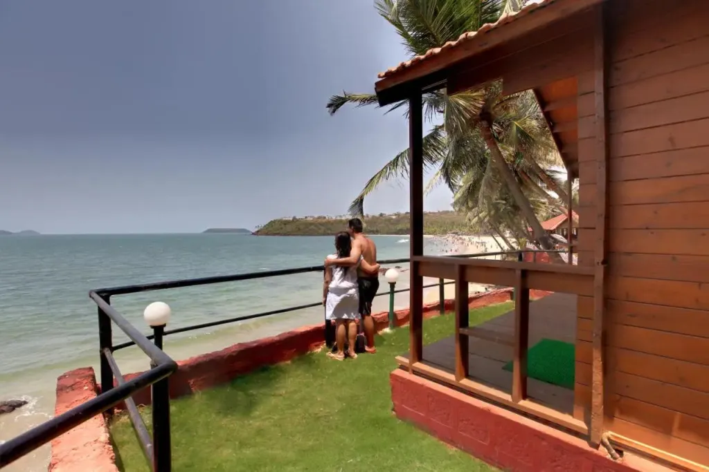 Un couple se tient sur une terrasse en bois face à la mer.