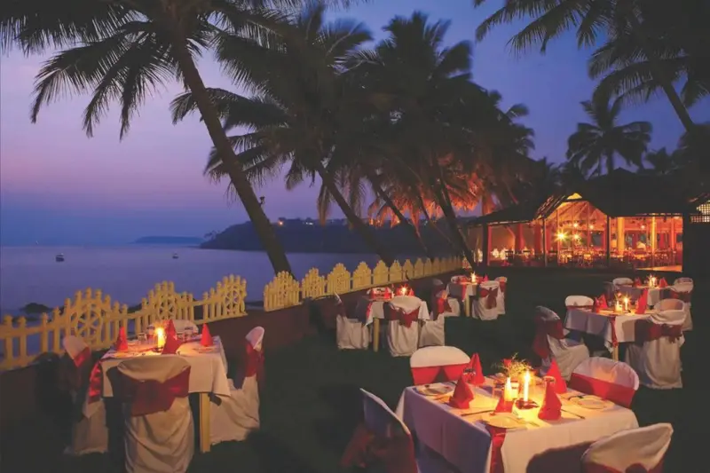 Tables dressées en extérieur avec vue sur la mer au coucher du soleil.