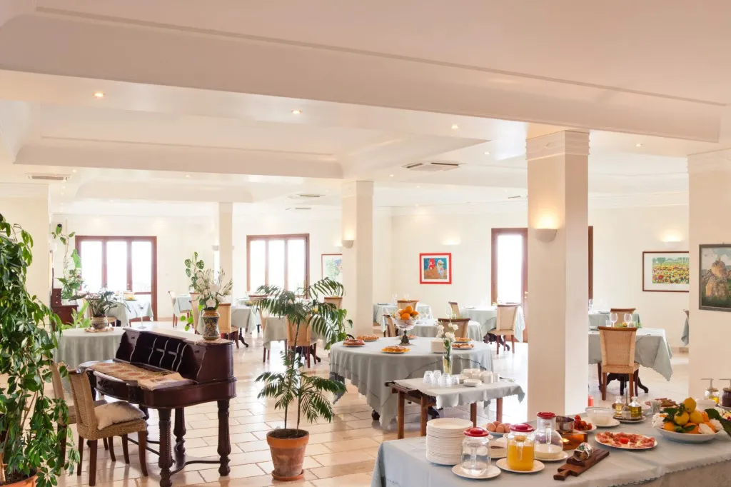 Une salle lumineuse est aménagée avec des tables dressées pour le repas.