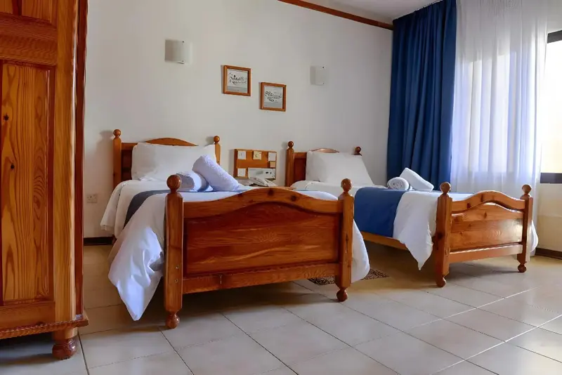 Une chambre lumineuse avec deux lits simples et une décoration sobre.