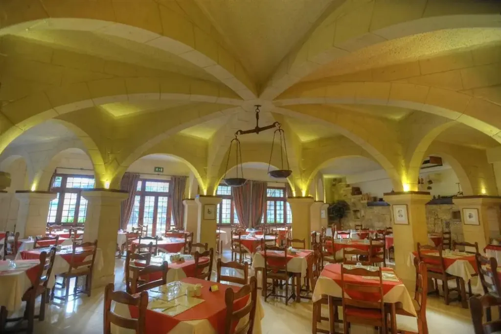 Une salle de restaurant voûtée avec des tables dressées pour le service.