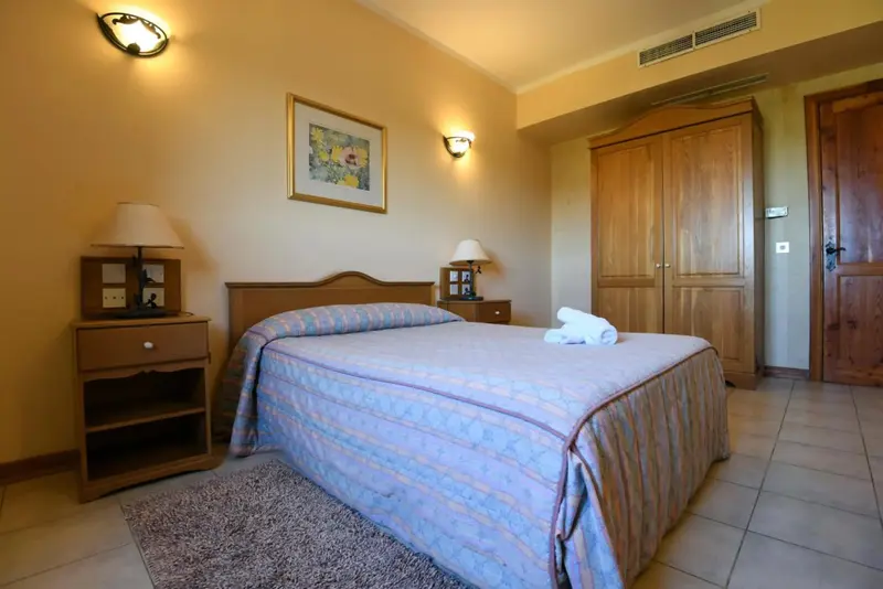 Une chambre lumineuse avec un lit double et un meuble de rangement.
