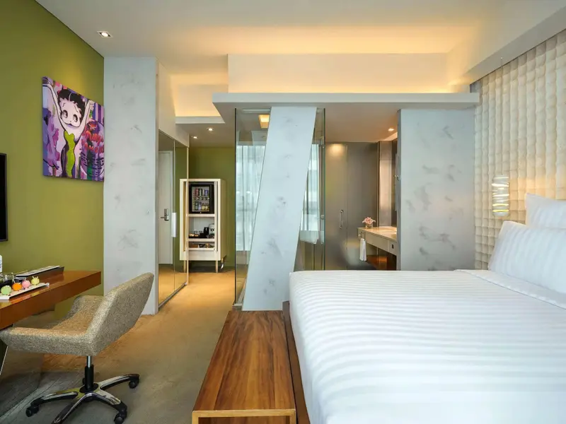 Une chambre lumineuse avec un lit blanc et un espace bureau.