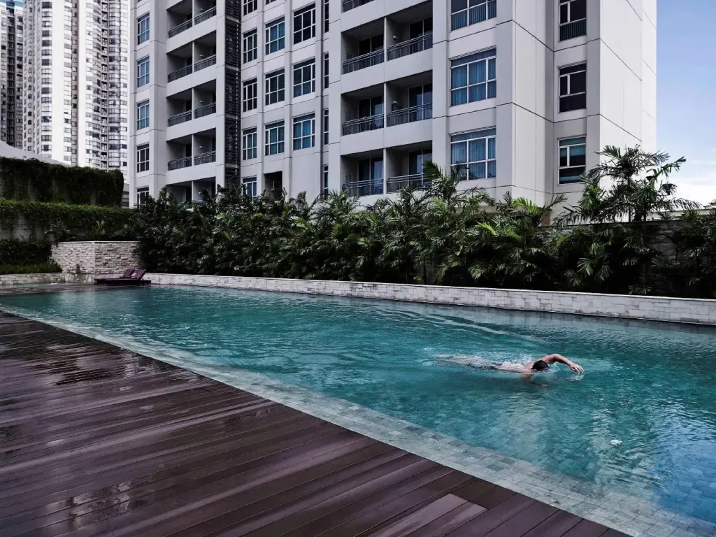 Une personne nage dans une piscine rectangulaire bordée d'un pont en bois.