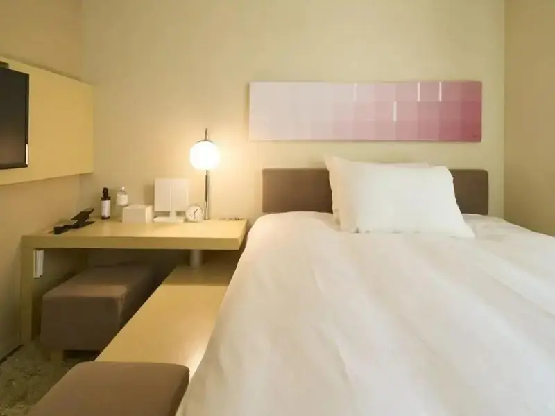 Une chambre lumineuse avec un lit blanc et un bureau.