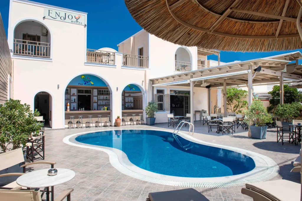 Une piscine bleue bordée d'une terrasse avec des transats et un bar.