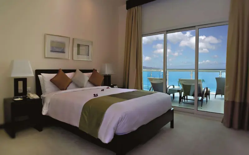 Une chambre lumineuse avec un grand lit donnant sur une vue mer.