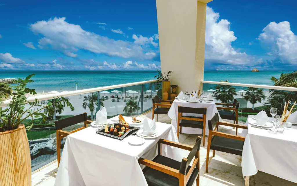 Tables dressées en terrasse avec vue sur la mer et le ciel nuageux.