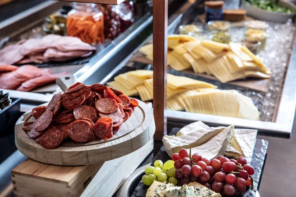 Présentation de charcuterie et de fromages variés sur un buffet.
