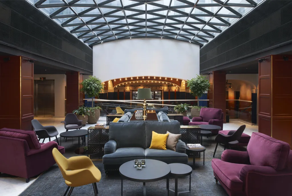 Un espace de détente intérieur avec des canapés et des fauteuils sous une verrière.