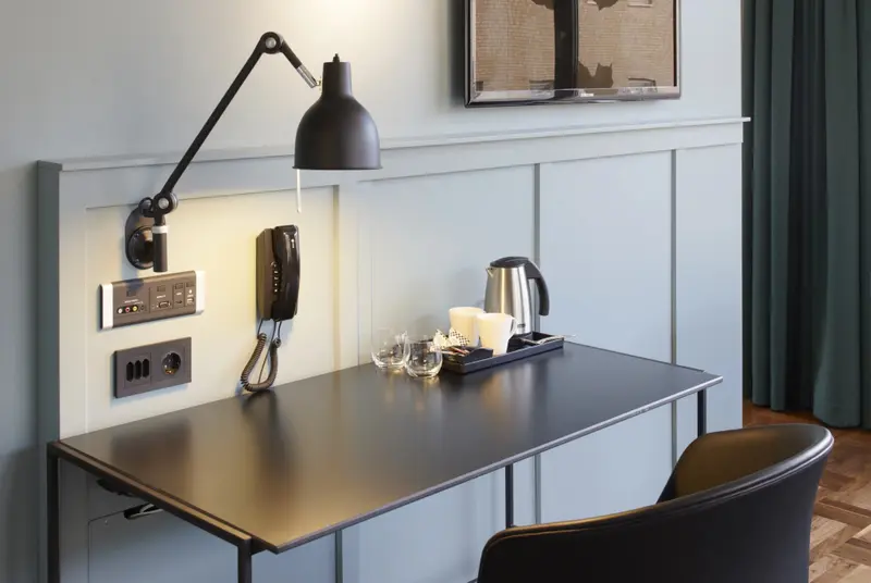 Un bureau avec une lampe et un téléphone dans une pièce décorée.