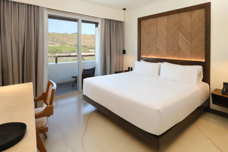 Une chambre lumineuse avec un grand lit et un accès à un balcon.