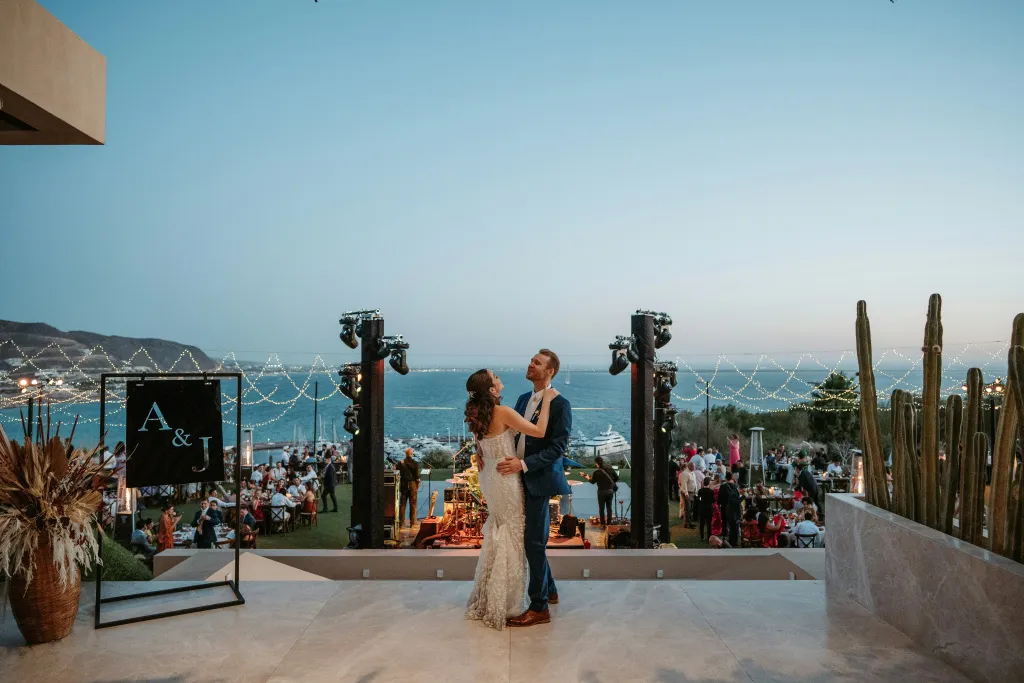 Un couple danse au crépuscule sur une terrasse surplombant la mer.